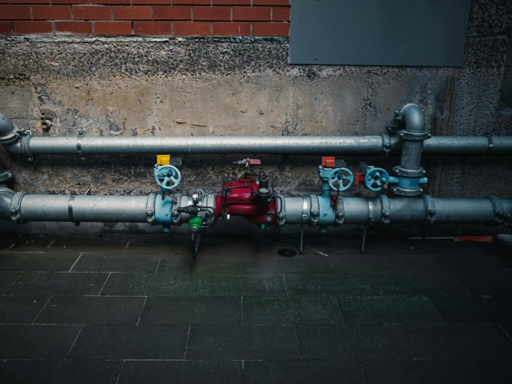 A detailed view of industrial pipes with colorful valves on a textured wall.